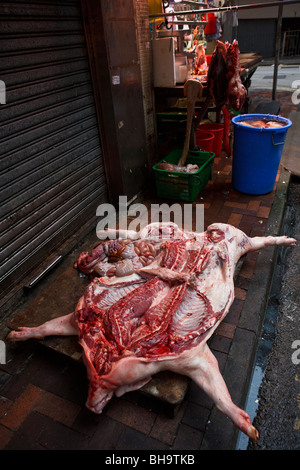 Un maiale la carcassa essendo disposta su un lato aria aperta butcher shop in Causeway Bay Hong Kong. Foto Stock