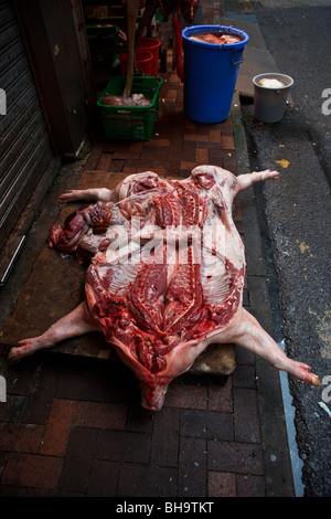 Un maiale la carcassa essendo disposta su un lato aria aperta butcher shop in Causeway Bay Hong Kong. Foto Stock