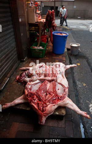 Un maiale la carcassa essendo disposta su un lato aria aperta butcher shop in Causeway Bay Hong Kong. Foto Stock