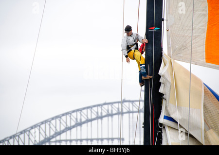 SYDNEY, Australia - Sydney, Australia - Membri di equipaggio che fissa una vela fino il montante di Lahana all'inizio del 2009 la Rolex Sydney Harbour Yacht Race nel porto di Sydney con il Sydney Harbour Bridge in background. Foto Stock