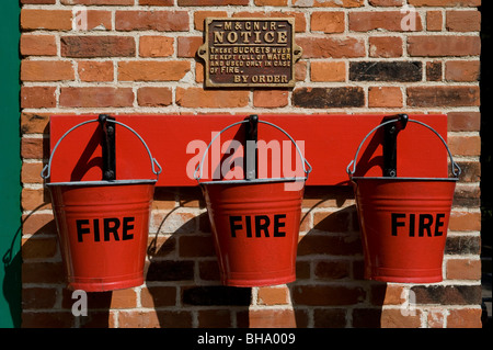 Rosso fuoco benne appesa sul muro di mattoni Foto Stock