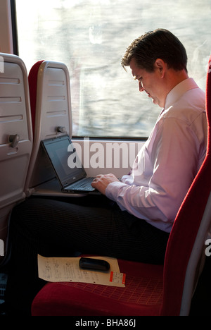 Business man " commuter " utilizzando il computer portatile sul passeggero viaggio in treno Foto Stock