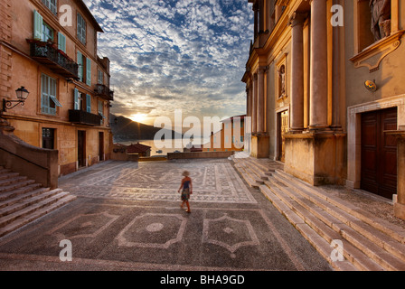 Una donna a piedi attraverso Parvis St Michel all'alba, la Città Vecchia, Menton, Cote d'Azur, alpi marittime, provenza, Francia Foto Stock