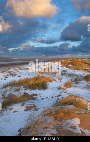 Neve che ricoprono le dune di sabbia e spiaggia a Holkham Bay sulla costa di Norfolk in inverno Foto Stock