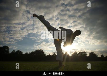 Giovane uomo esegue il Karate kick davanti ad un tramonto REGNO UNITO Foto Stock