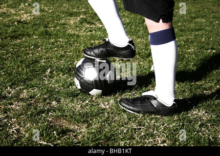 Giocatore di calcio con il piede sulla parte superiore del calcio Foto Stock