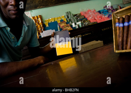 Un uomo cubano offrendo una finta di sigari Cohiba sotto il contatore in uno stato negozio di generi alimentari a l'Avana, Cuba. Foto Stock
