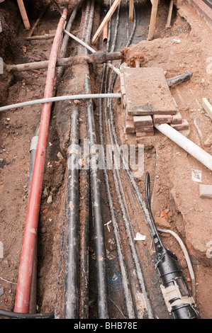 Esposti elettrica, del gas e delle telecomunicazioni i cavi e tubi di acqua durante la guida su strada e sentiero opere. Foto Stock