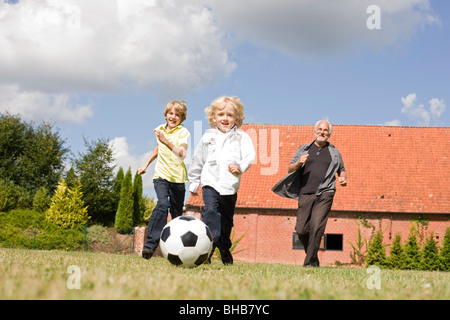 Nonno e i bambini a giocare a calcio Foto Stock