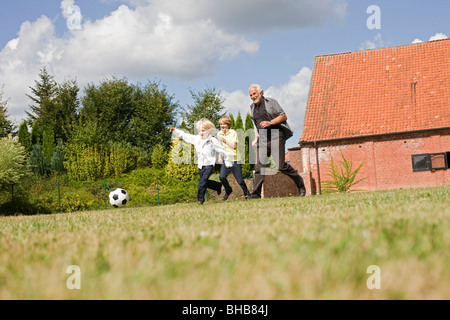 Nonno e i bambini a giocare a calcio Foto Stock