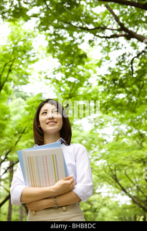 Giappone, nella prefettura di Osaka, imprenditrice guardando in alto, sorridente, basso angolo di visione Foto Stock