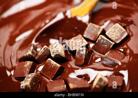 Il cucchiaio di legno di agitazione ricca fusione aggiungete pezzetti di cioccolato Foto Stock