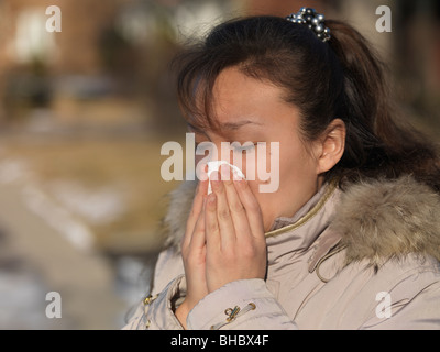 Donna soffia il naso all'aperto in inverno Foto Stock
