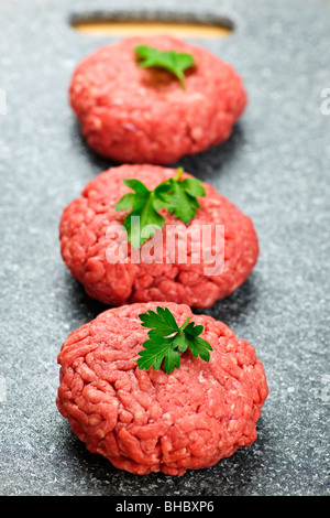 Tre di macinato di manzo polpette di hamburger sul bordo di taglio Foto Stock
