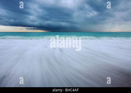 La spiaggia di Nizza sotto un clima burrascoso e nuvoloso giorno fotografato con un obiettivo grandangolare con una bassa esposizione Foto Stock