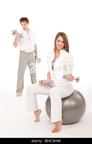 Giovane coppia sano allenamento con i pesi e palla fitness su bianco Foto Stock