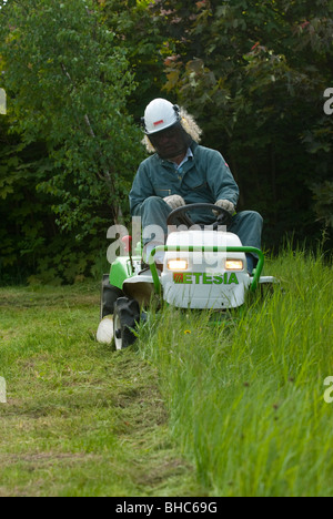 Erba di fresatura con un Etesia sedersi sul tosaerba Foto Stock