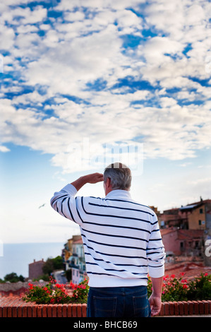Senior uomo guardando alla vista di Capoliveri, Isola d'Elba, Italia Foto Stock