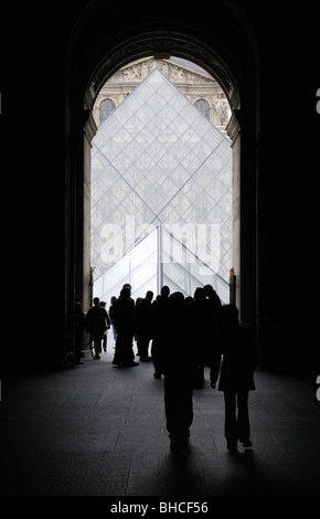 Vista del museo del Louvre piramide in vetro attraverso un ingresso con turisti Foto Stock