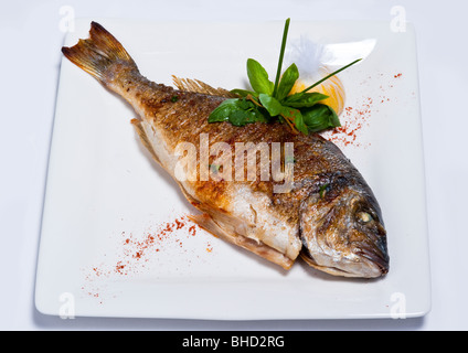 La frittura di pesce è preparato al ristorante su una piastra bianca. Tablewares su ciascun lato Foto Stock