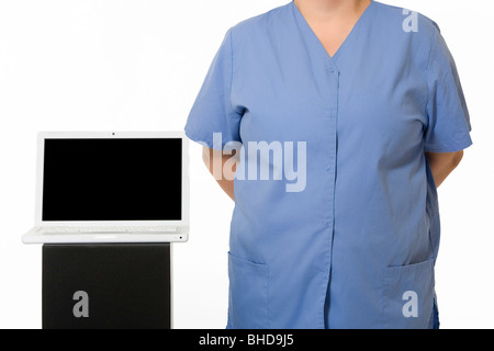 Una femmina di infermiere ritratto in piedi accanto a un computer portatile. Foto Stock