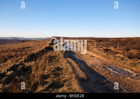 In inverno il sole sulla lunga strada rialzata, Stanage bordo nel Peak District Foto Stock