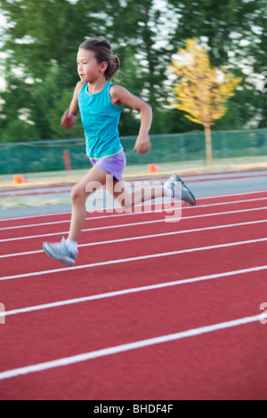 Razza mista Ragazza che corre sulla via Foto Stock