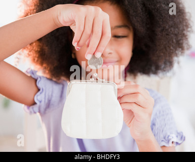 Ragazza ispanica mettendo moneta nella borsa Foto Stock