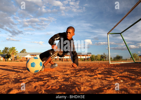 Un portiere di calcio si tuffa per salvare il colpo al traguardo su un passo di sabbia di fronte a pali in Sud Africa settentrionale di Cape. Foto Stock