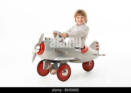 Ragazzo seduto in aeroplano giocattolo Foto Stock