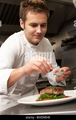 Chef di aggiungere il Condimento al piatto in un ristorante Cucina Foto Stock