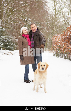 Coppia senior cane a piedi attraverso il bosco innevato Foto Stock