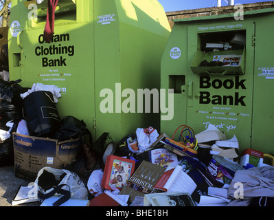 Regno Unito libro e abbigliamento cassonetti per il riciclaggio traboccante di pile di libri e vestiti a terra Foto Stock