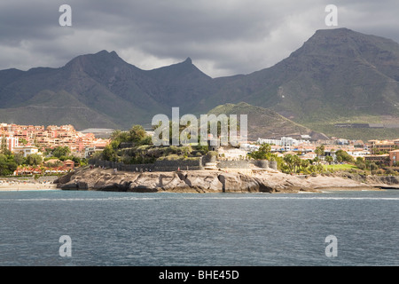 Le montagne vulcaniche torre al di sopra di edifici della città di Los Cristianos sulla costa di Tenerife, Spagna. Foto Stock