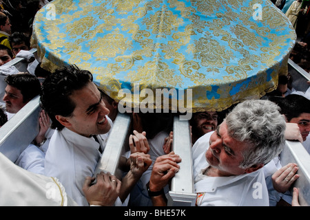 La fraternità membri esercitino il trono pesanti e immettere la porta stretta della Chiesa durante la Pasqua a Malaga, Spagna. Foto Stock