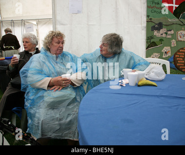 Due vecchi signori in plastica mac conversando davanti ad una tazza di tè a Chatsworth Country Fair, la Chatsworth House, Derbyshire, England, Regno Unito Foto Stock