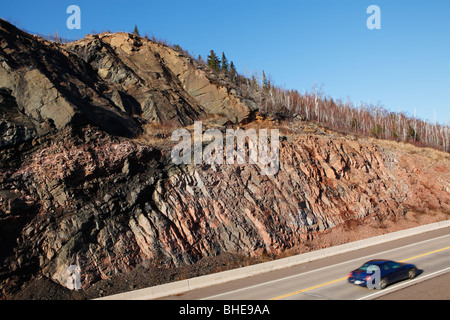 Una strada tagliata lungo l'autostrada 61 nel nord del Minnesota attraverso antiche rocce vulcaniche vicino Lago Superiore. Foto Stock