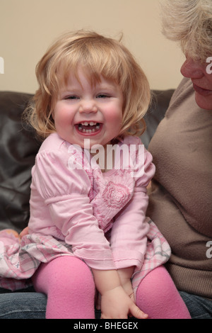 Bambina con capelli biondi sat sulla donna del ginocchio Foto Stock