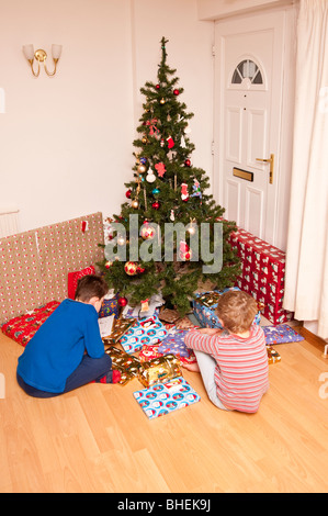 Un modello rilasciato foto di due fratelli aprendo i loro regali di Natale sotto l'albero nel Regno Unito Foto Stock