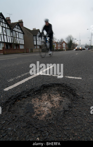 Ciclista passa gran profonda buca in strada Foto Stock