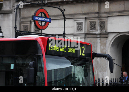 Red London Bendy Bus con il logo della metropolitana in background Foto Stock