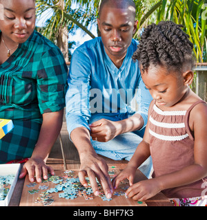 Uomo nero con la figlia risolvendo puzzle Foto Stock