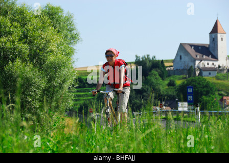 Ciclista femmina, Chiesa di San Nicholas, Danubio Percorso Ciclabile Passau Vienna, Austria Inferiore, Austria Foto Stock