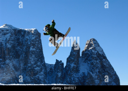 Uno snowboarder durante un salto in avanti di montagne e il cielo blu, Dolomiti, Alto Adige, Italia, Europa Foto Stock