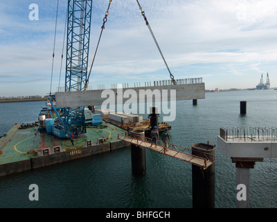 Grandi gru galleggiante il sollevamento di una trave di calcestruzzo in posizione durante la creazione di una stazione docking pier per una grande nave di petrolio, Botlek Foto Stock