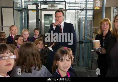 David Cameron MP di organizzare un gruppo di bambini della scuola primaria per guardare la fotocamera mentre si visita Senedd, Cardiff Foto Stock