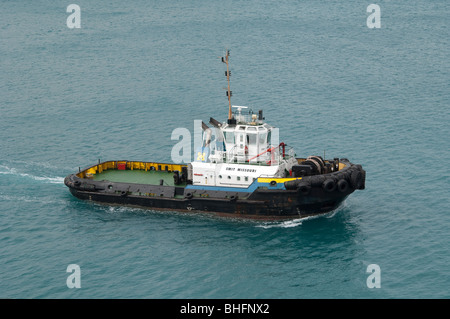 Il 'Smit Missouri ' rimorchiatore motori attraverso il porto di fornire assistenza a un altro ocean andando nave da carico. Foto Stock