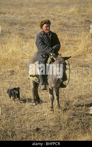 Un pastore kazako o pastore con il suo asino e cane nelle steppe del Kazakistan Foto Stock