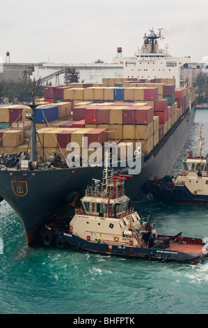 Rimorchiatore 'Svitzer Grand Bahama' appiles potere di prua di 'MSC Uganda' in uno sforzo per manovrare la nave fuori del porto. Foto Stock