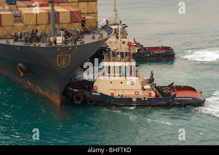 Rimorchiatore 'Svitzer Grand Bahama' appiles potere di prua di 'MSC Uganda' in uno sforzo per manovrare la nave fuori del porto. Foto Stock